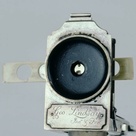 Detail of a collapsible single-lens microscope showing lens and slide