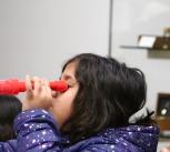 Young visitor in the Learning Gallery using a red telescope.