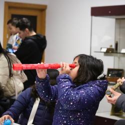 Young visitor in the Learning Gallery using a red telescope.