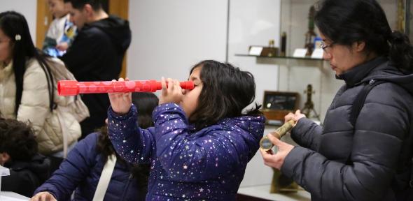 Twilight at the Whipple Museum Young visitor in the Learning Gallery using a red telescope.