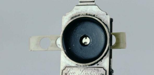 Detail of a collapsible single-lens microscope showing lens and slide